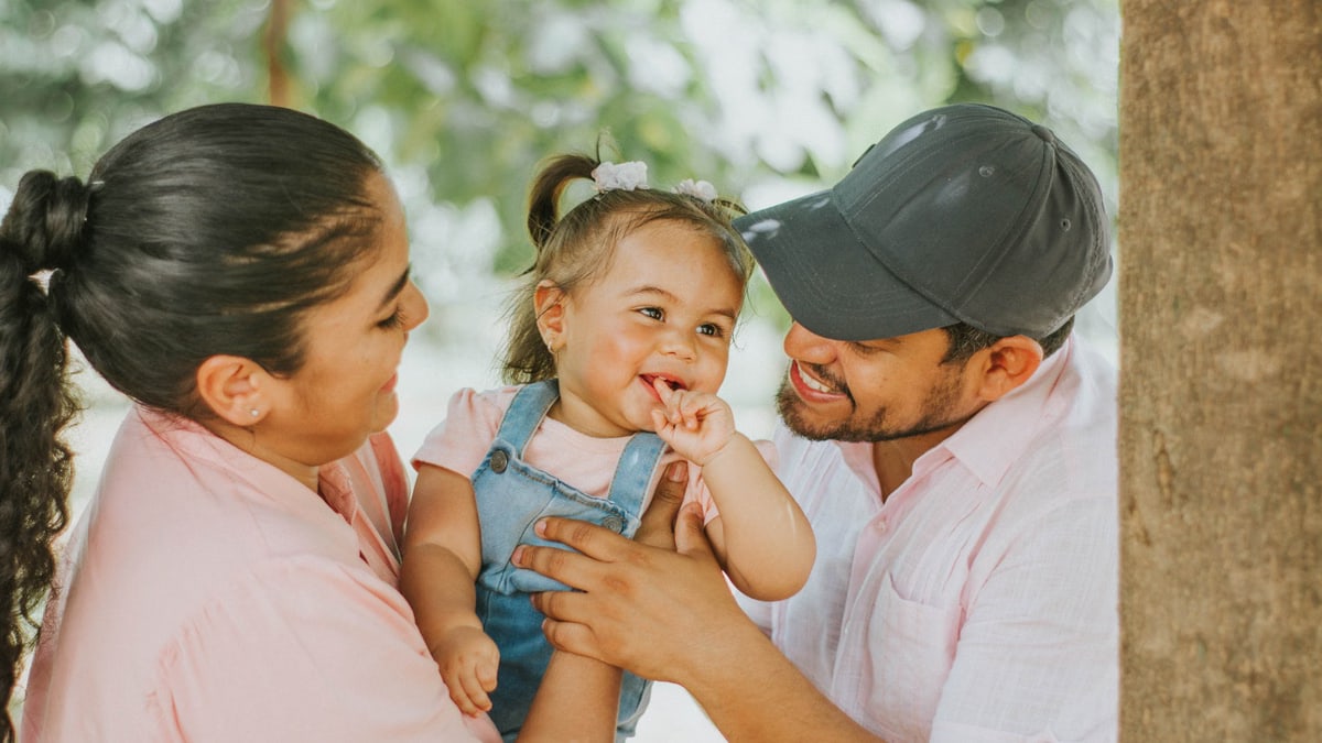 Smiling parents with baby enjoying a day outdoors in Guayaquil park.